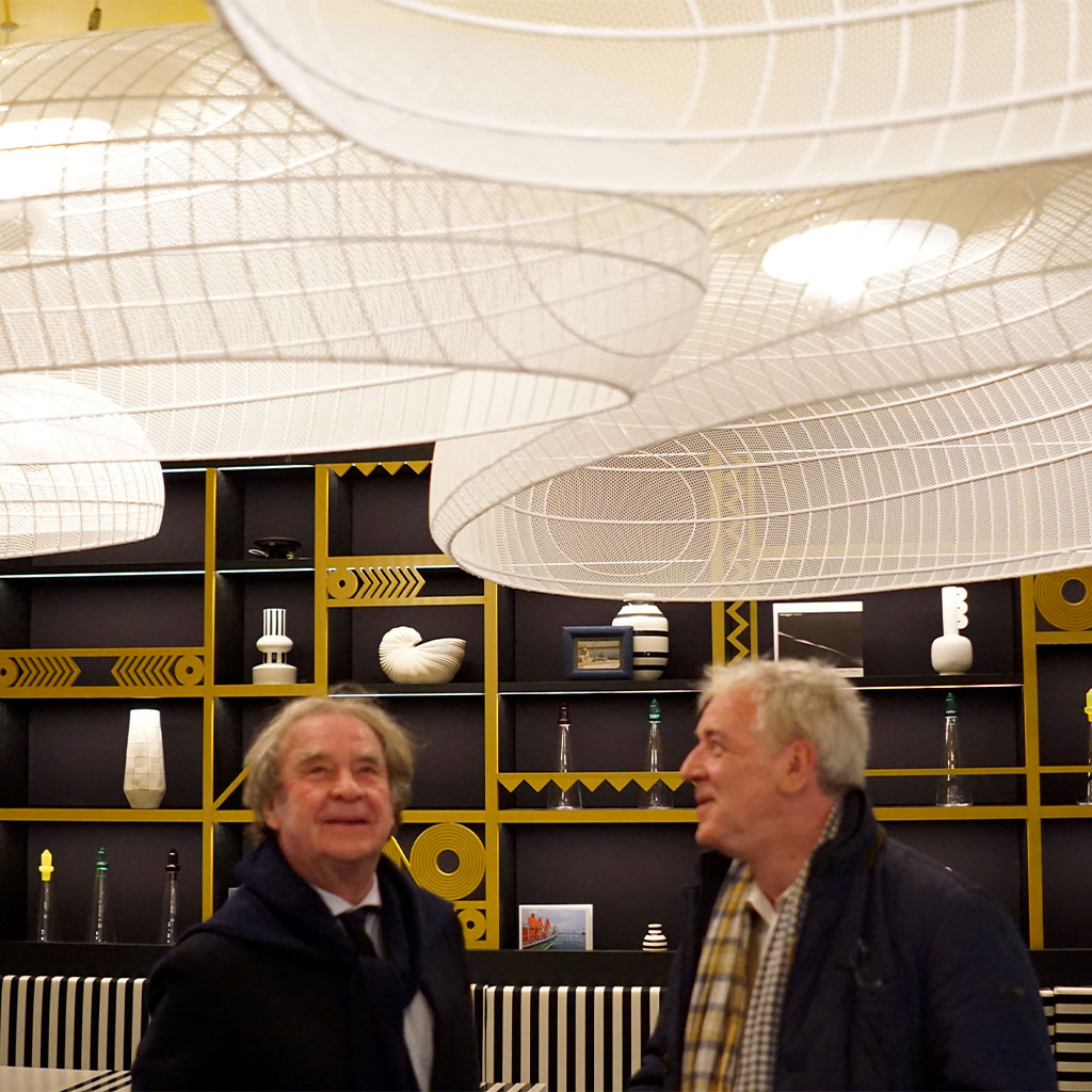 Deux hommes admirant les luminaires en métal blanc dans un restaurant design