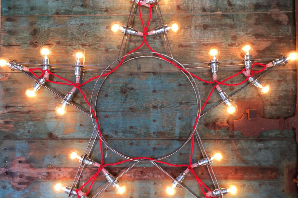 Étoile lumineuse en métal avec guirlande d’ampoules sur fond en bois vieilli