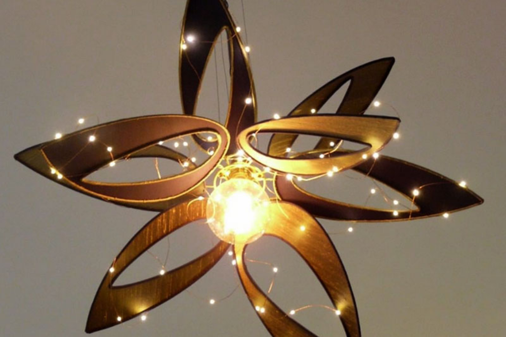 Suspension lumineuse en forme de fleur, composée de pétales ajourés en bois et ornée de guirlandes LED scintillantes autour d’une ampoule centrale