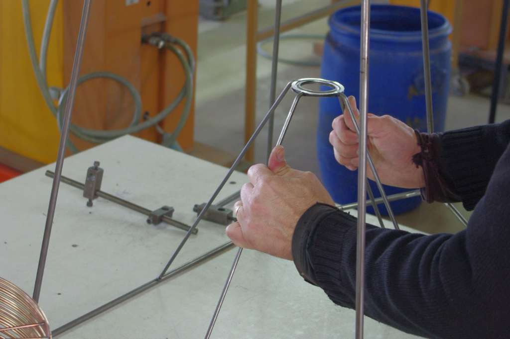 Artisan assemblant une structure métallique pour un luminaire sur un plan de travail
