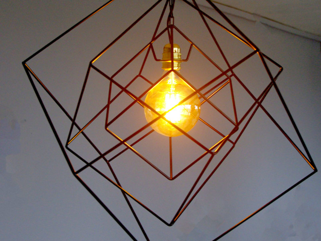 Suspension design en métal avec une ampoule à filament, encadrée par des cubes imbriqués pour un effet géométrique moderne