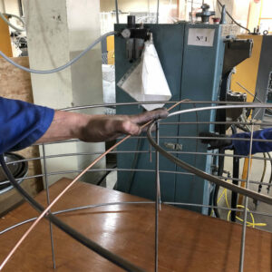 Artisan travaillant sur la structure métallique d'un luminaire dans un atelier